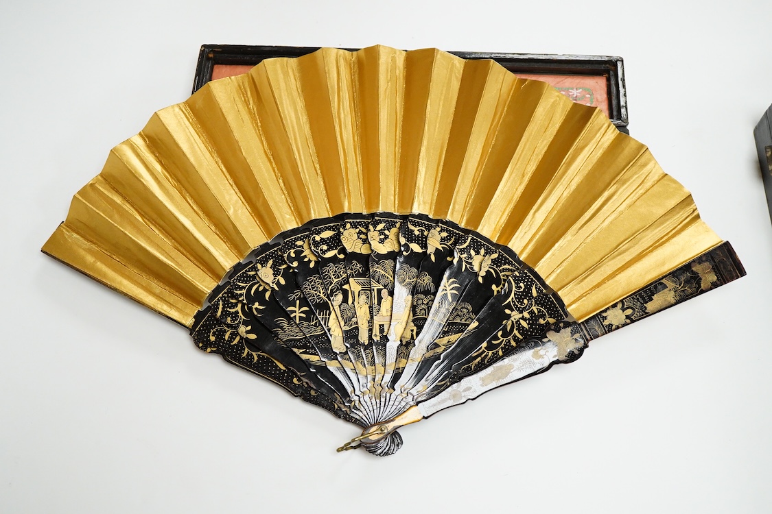 Four 19th century Chinese gilt-decorated black lacquer fans with figure painted leaves, two cased, largest 41cm